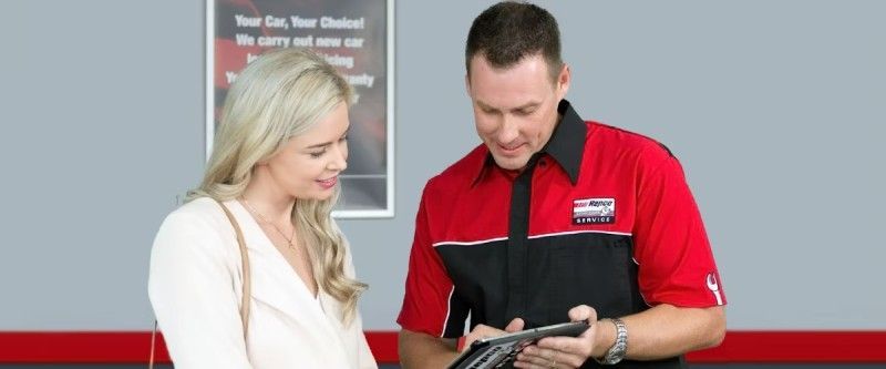 A Man In A Red Shirt Is Talking To A Woman In A White Shirt — Hervey Bay Service Centre in Pialba, QLD