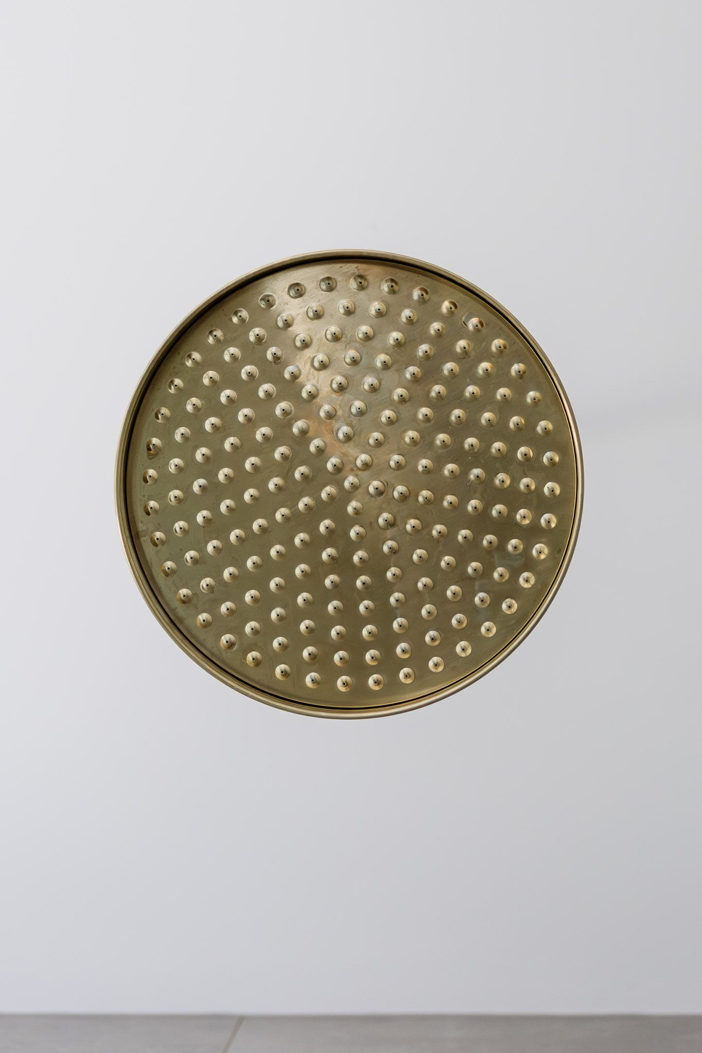 Golden, round tray with a textured surface featuring many raised dots, set against a white background.