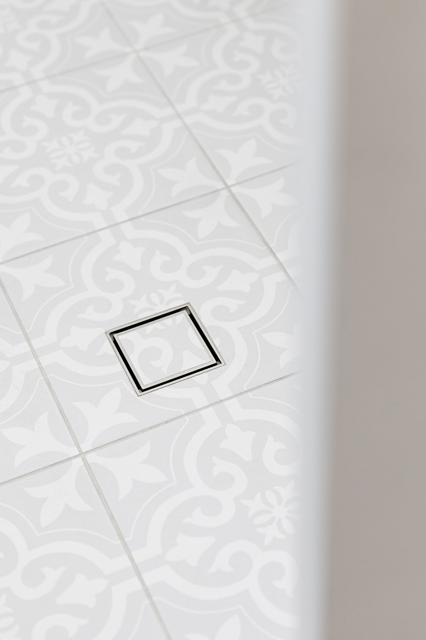 Tile floor with a decorative pattern and a square drain.