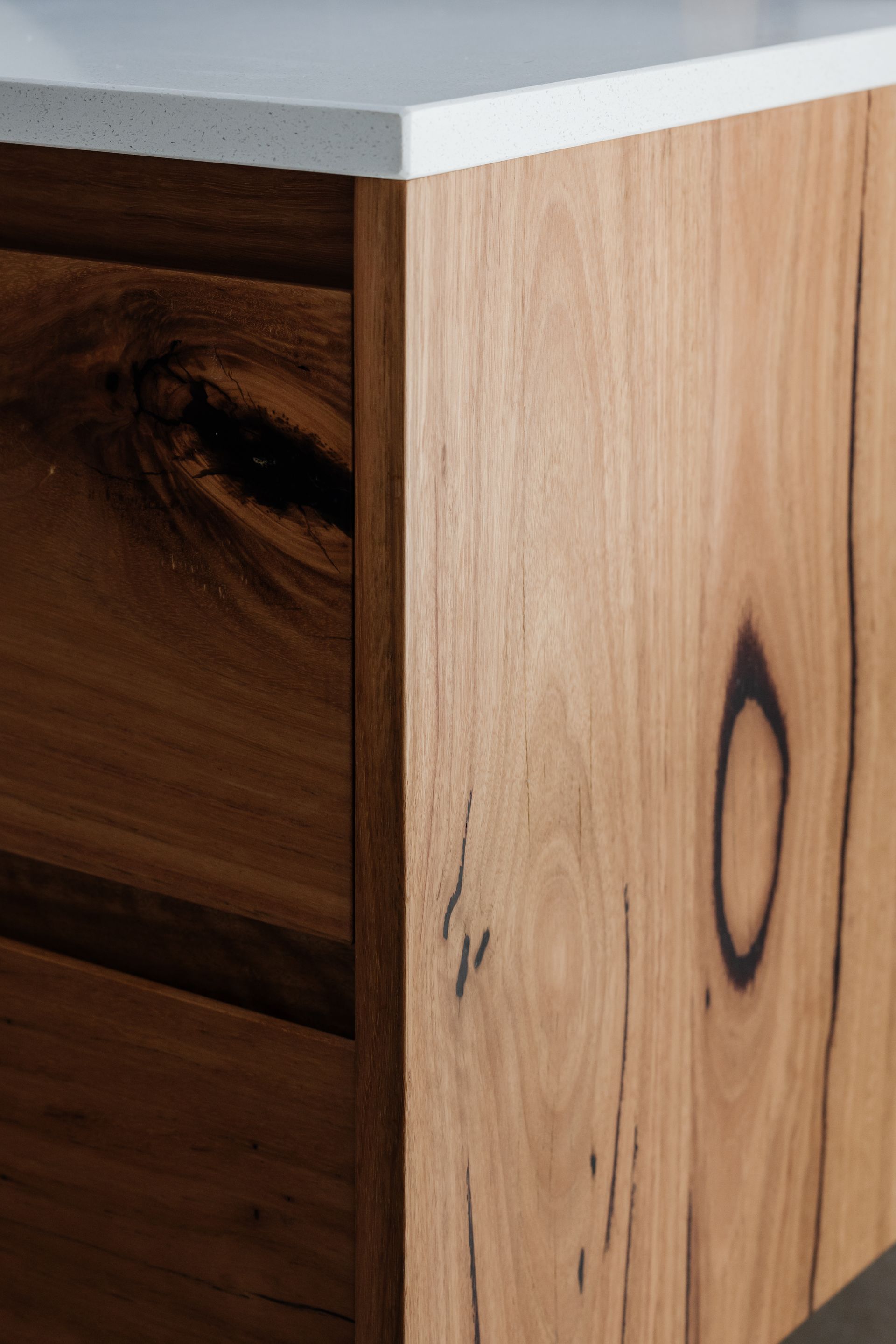 Close-up of a wooden cabinet with a white countertop. The cabinet has visible wood grain and a drawer.