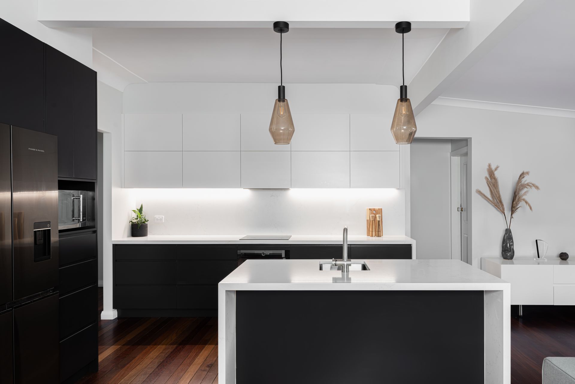 Modern kitchen with black and white cabinets, island, and pendant lights.