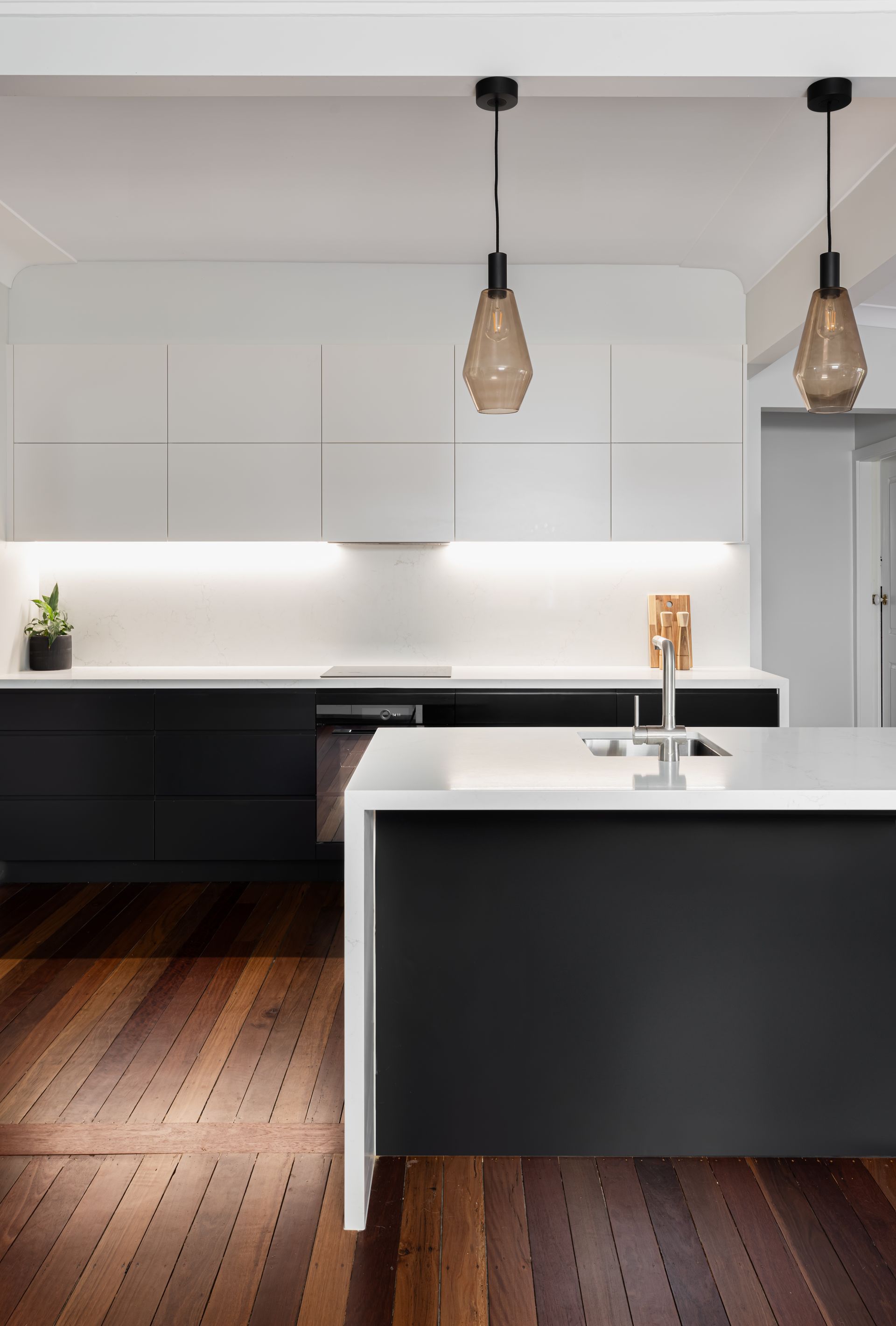Modern kitchen with white and black cabinets, island, and pendant lights.