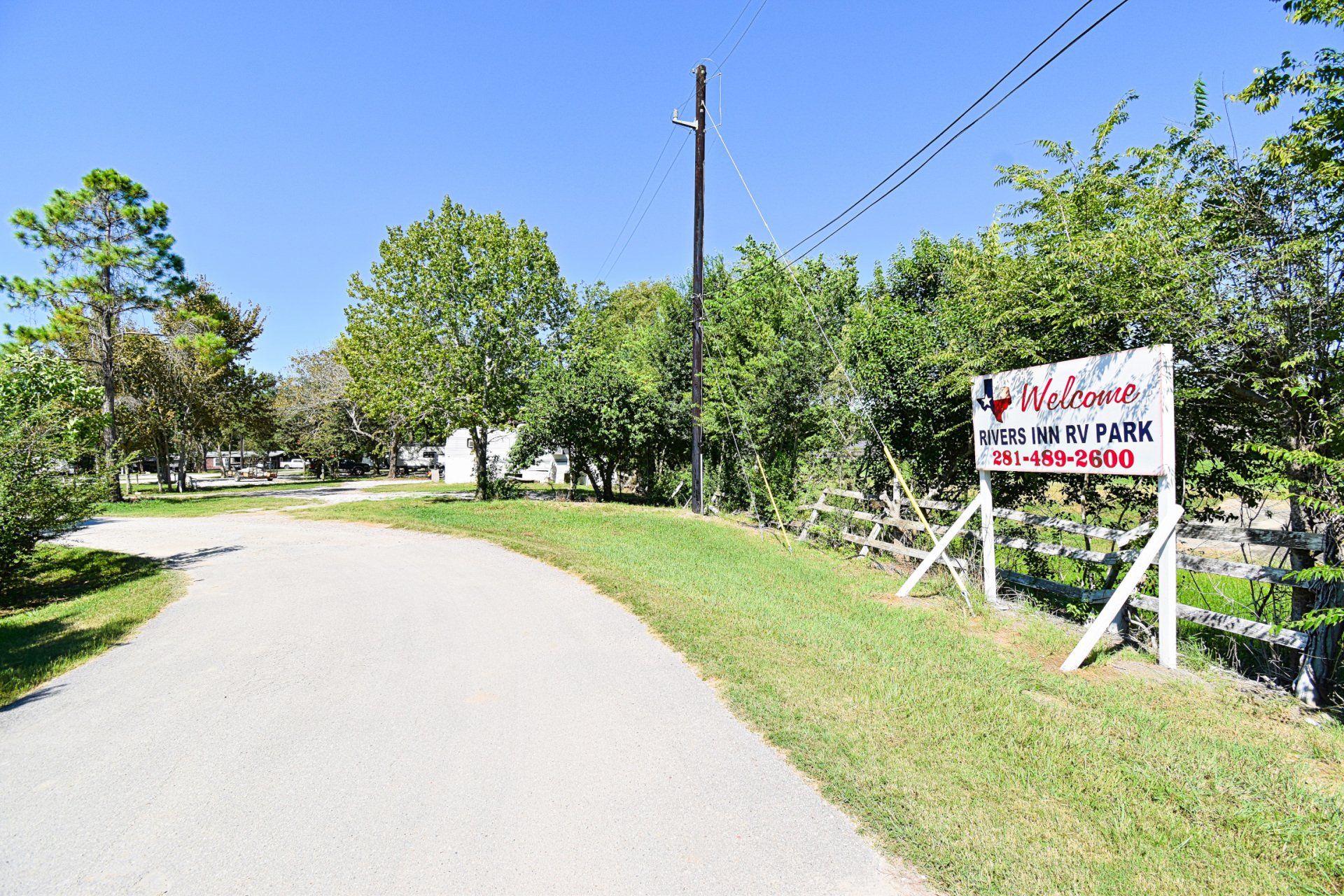 Brick building with a stone entrance, two parked cars, and large rocks in the foreground under a blue sky.