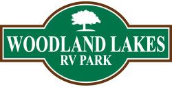 Woodland Lakes RV Park logo: green and brown with a tree graphic and white text.
