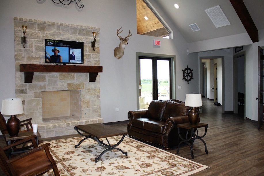 Living room with stone fireplace, TV, leather sofa, and deer head mount.
