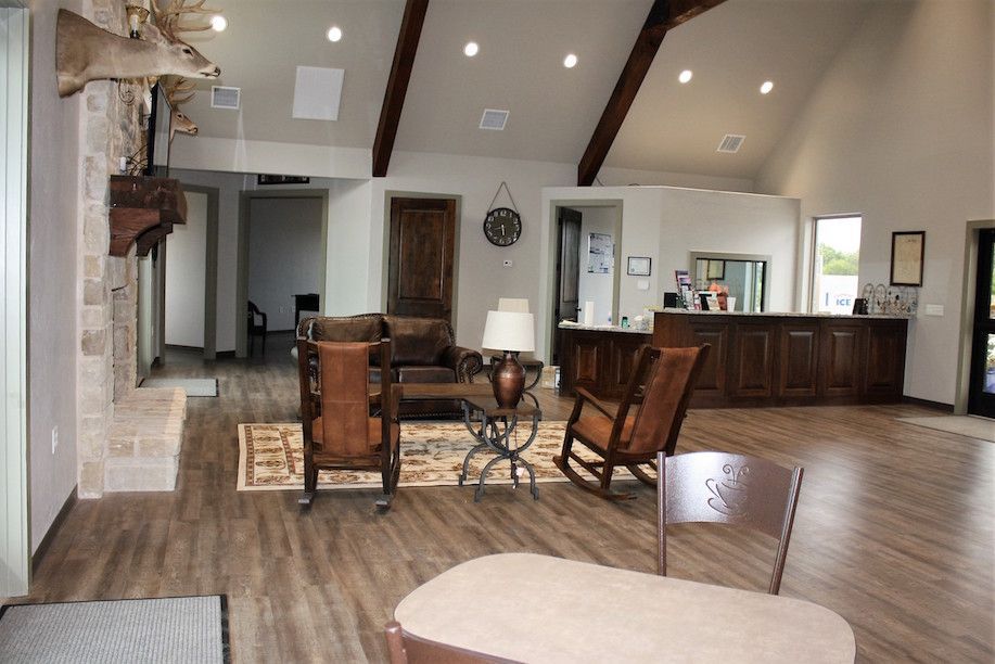 Lobby with wood floors, stone fireplace, rocking chairs, and a reception desk.