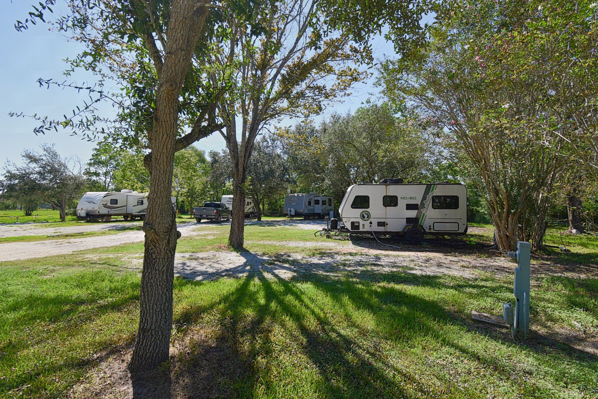 Row of white washing machines in a laundry room, against a tan wall, and a gray-brown floor.