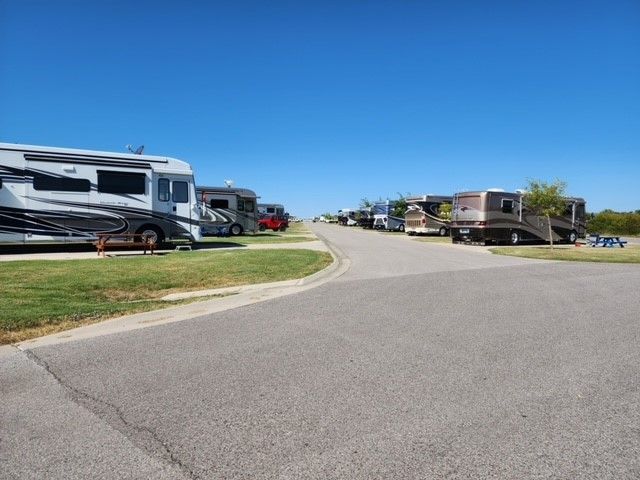 RV park with several recreational vehicles parked along a paved road under a blue sky.