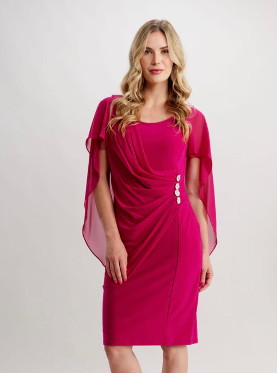 A woman is wearing a pink dress with a cape on the sleeves.