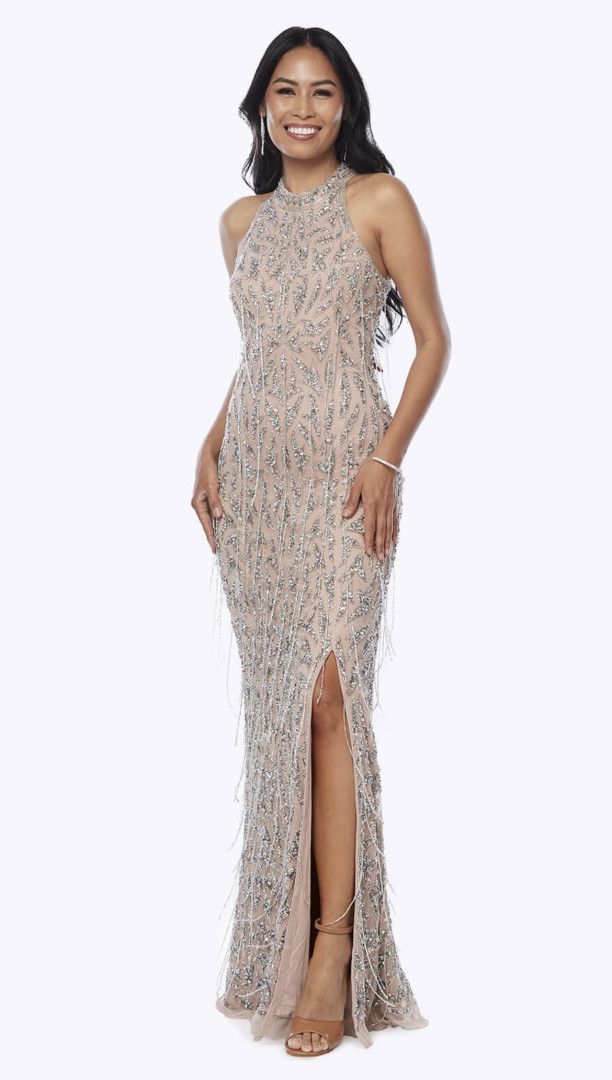 Woman in beaded gown with a high slit, posing with a smile against a white background.