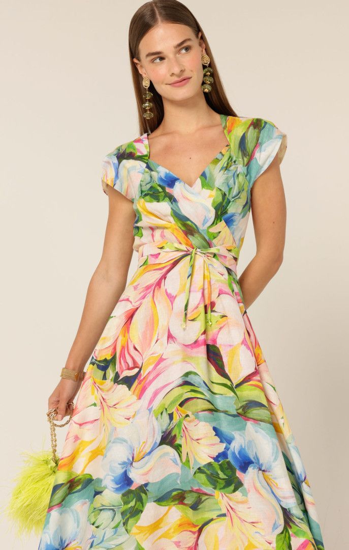 Woman in floral dress, holding a yellow purse, smiling.