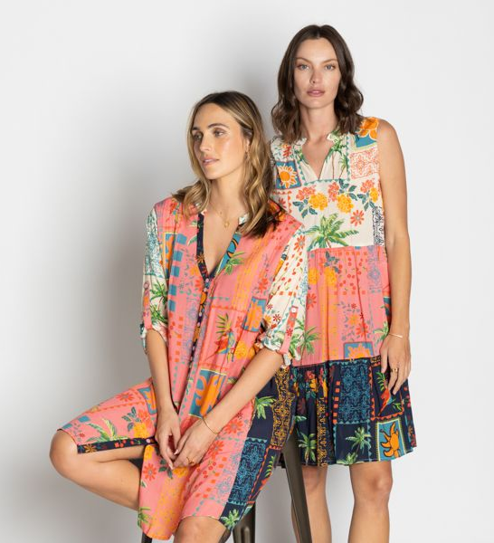 Two women wearing patchwork dresses in front of a white backdrop.