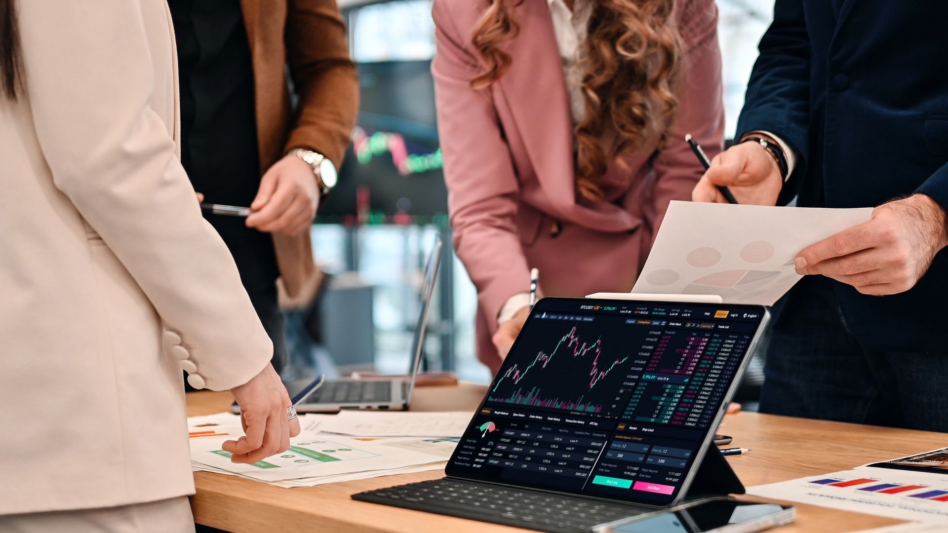 Two people reviewing financial data on a laptop, using a calculator, and pointing at charts.