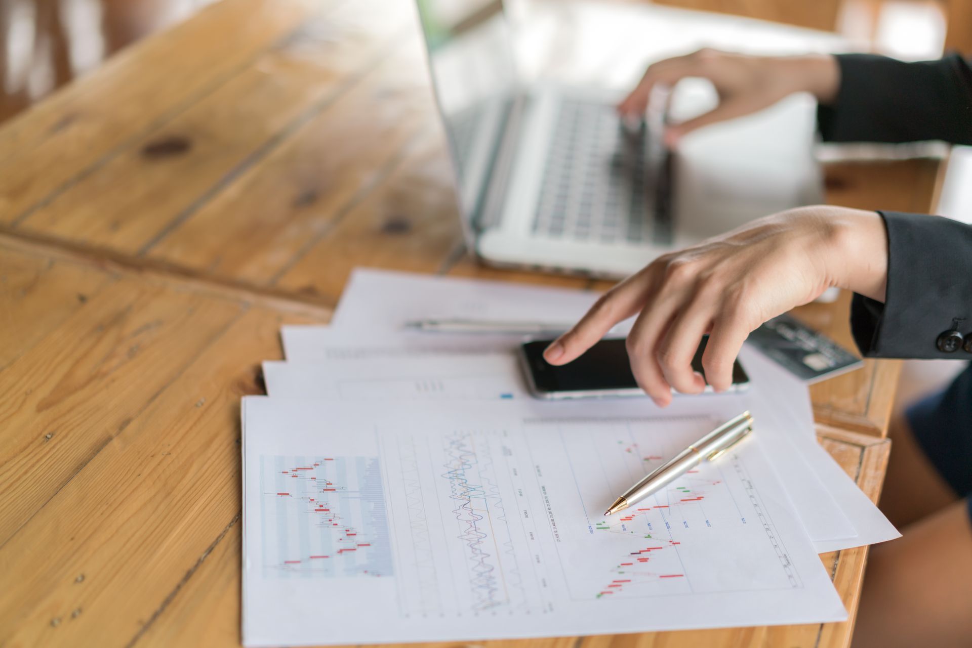 Two people reviewing financial data on a laptop, using a calculator, and pointing at charts.