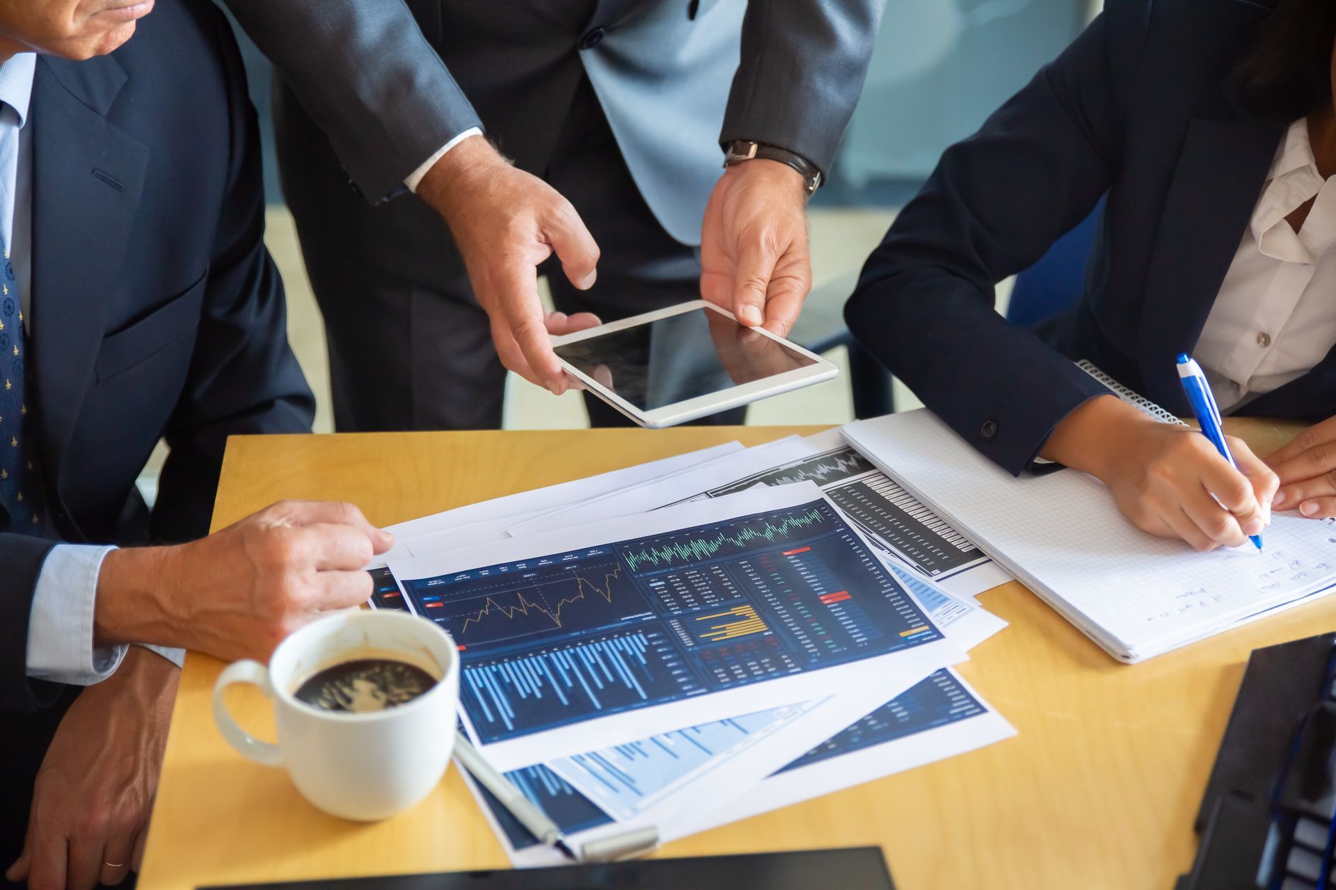 Two people reviewing financial data on a laptop, using a calculator, and pointing at charts.