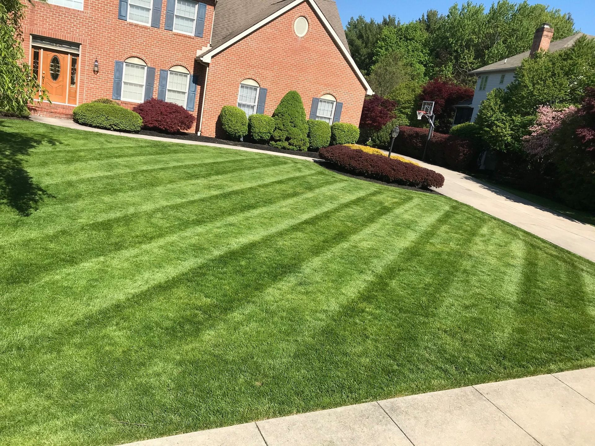 A large brick house with a lush green lawn in front of it.