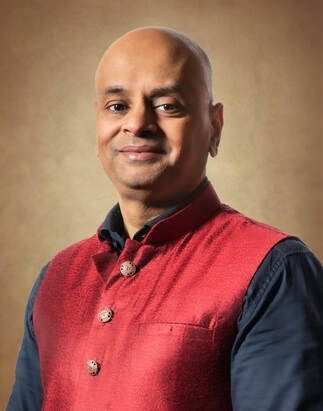 Bald man in red vest, smiling, looking at the camera.
