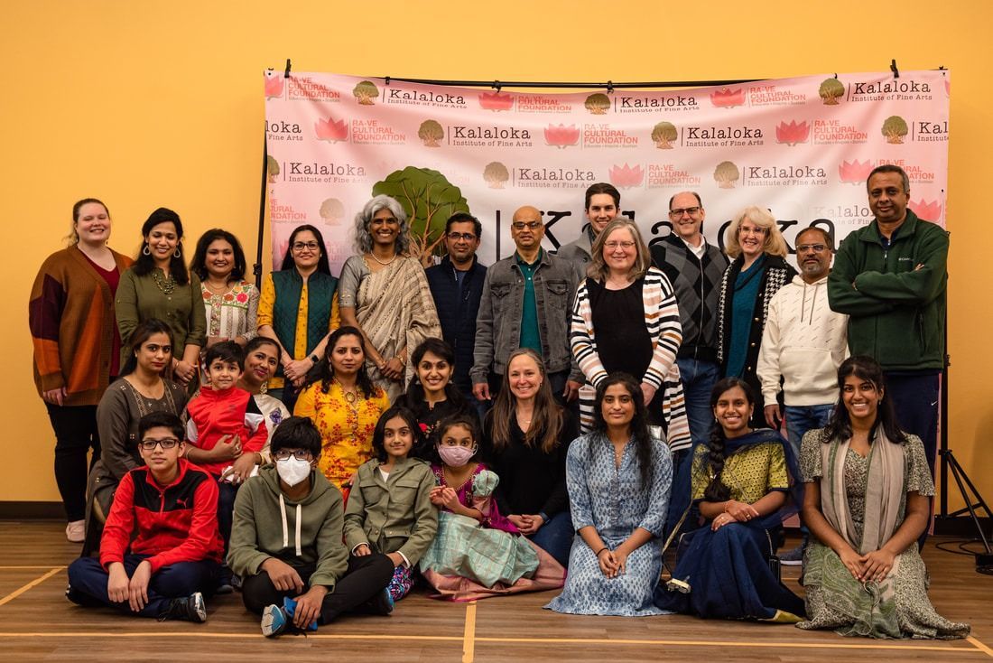 Group of people posing for a photo in front of a banner. Many are smiling, some are children.
