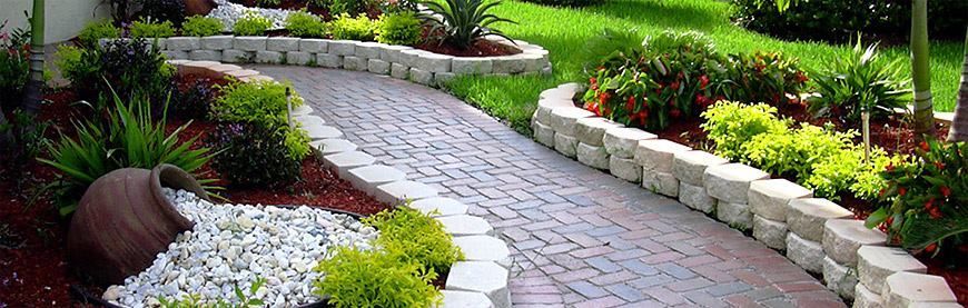 A brick walkway in a garden surrounded by plants and rocks.