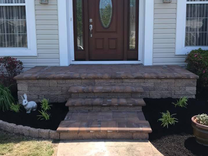 A brick porch with steps leading to the front door of a house.