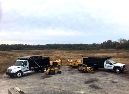 A group of trucks and tractors are parked in a field.