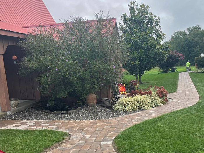 A brick walkway leading to a house with a red roof.