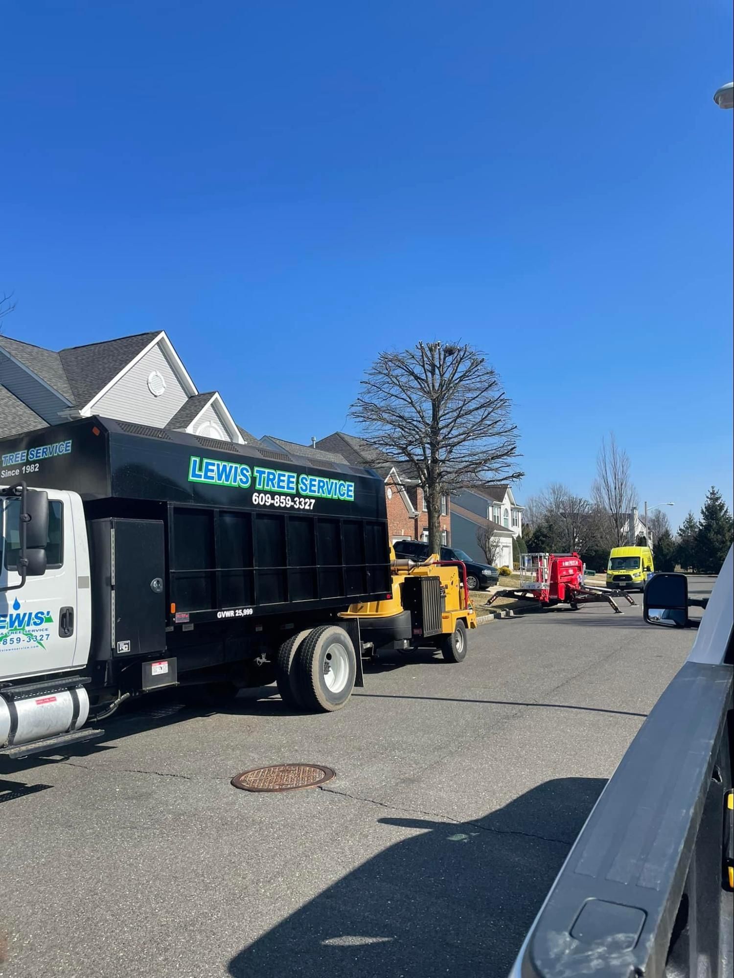 A dump truck is parked in a parking lot in front of a house.
