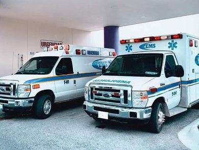 Dos ambulancias blancas estacionadas afuera de un edificio con un cartel de