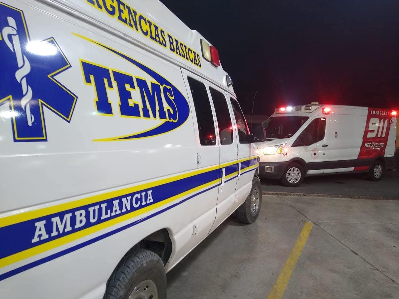 Dos ambulancias con luces intermitentes de noche. Una con la etiqueta