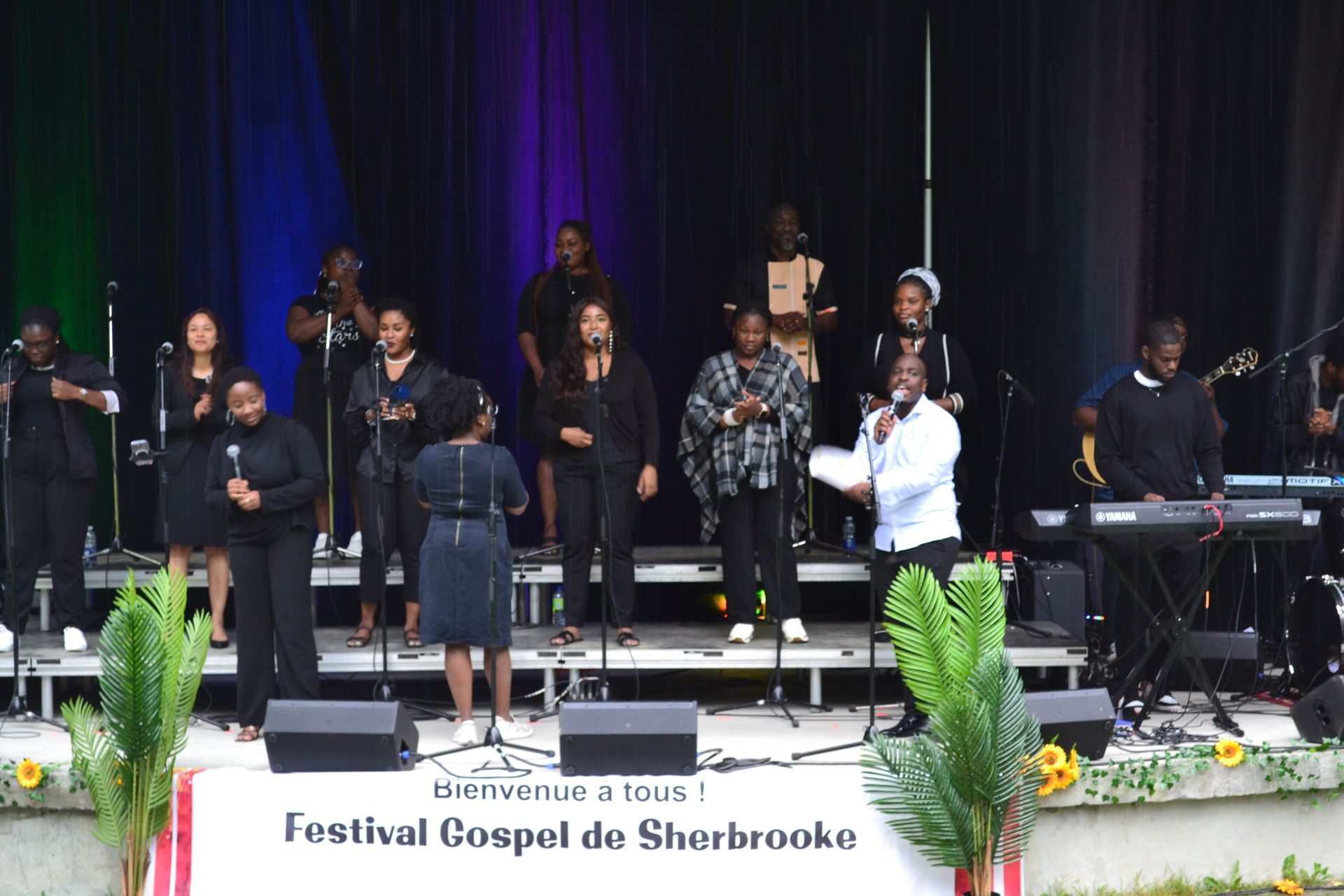 Un groupe de personnes chantant devant un panneau indiquant festival gospel de sherbrooke