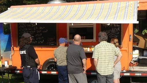 Un groupe de personnes debout devant un food truck orange