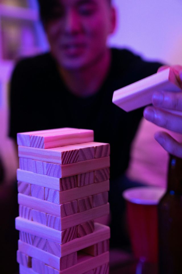 Un homme joue au Jenga avec une pile de blocs de bois