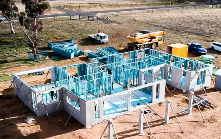 An Ariel View Of A Construction Site With Blue Scaffolding On A Field Next To A Road — Precast Concrete Solutions in Queanbeyan East, NSW