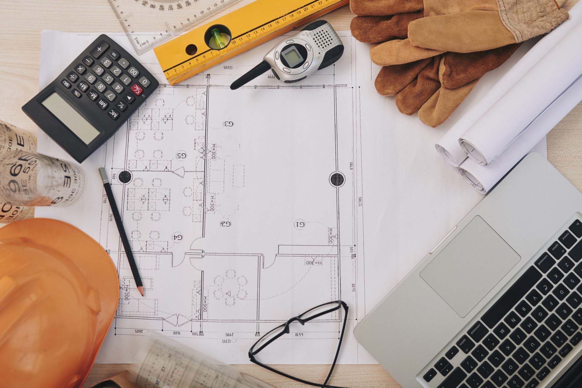 A Laptop is Sitting on top of a Table next to a Blueprint — Precast Concrete Solutions in Queanbeyan East, NSW