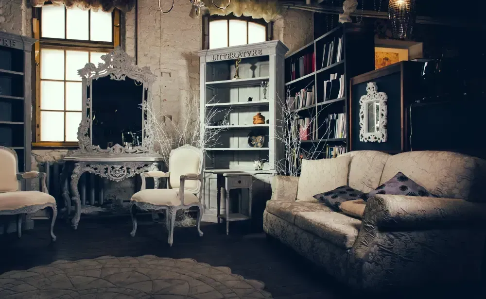 A living room with a couch , chairs , shelves and a mirror.