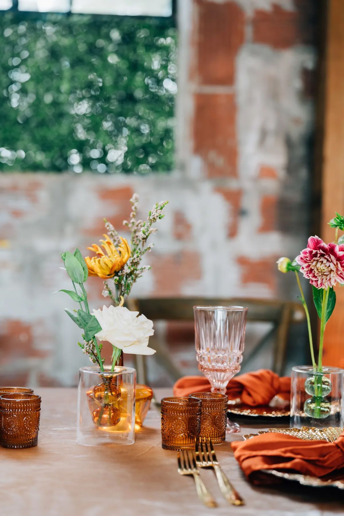 A table with plates , glasses , vases , and flowers on it.