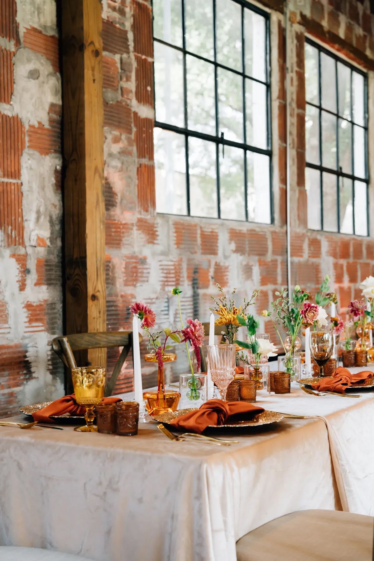 A table set for a wedding reception in front of a brick wall.