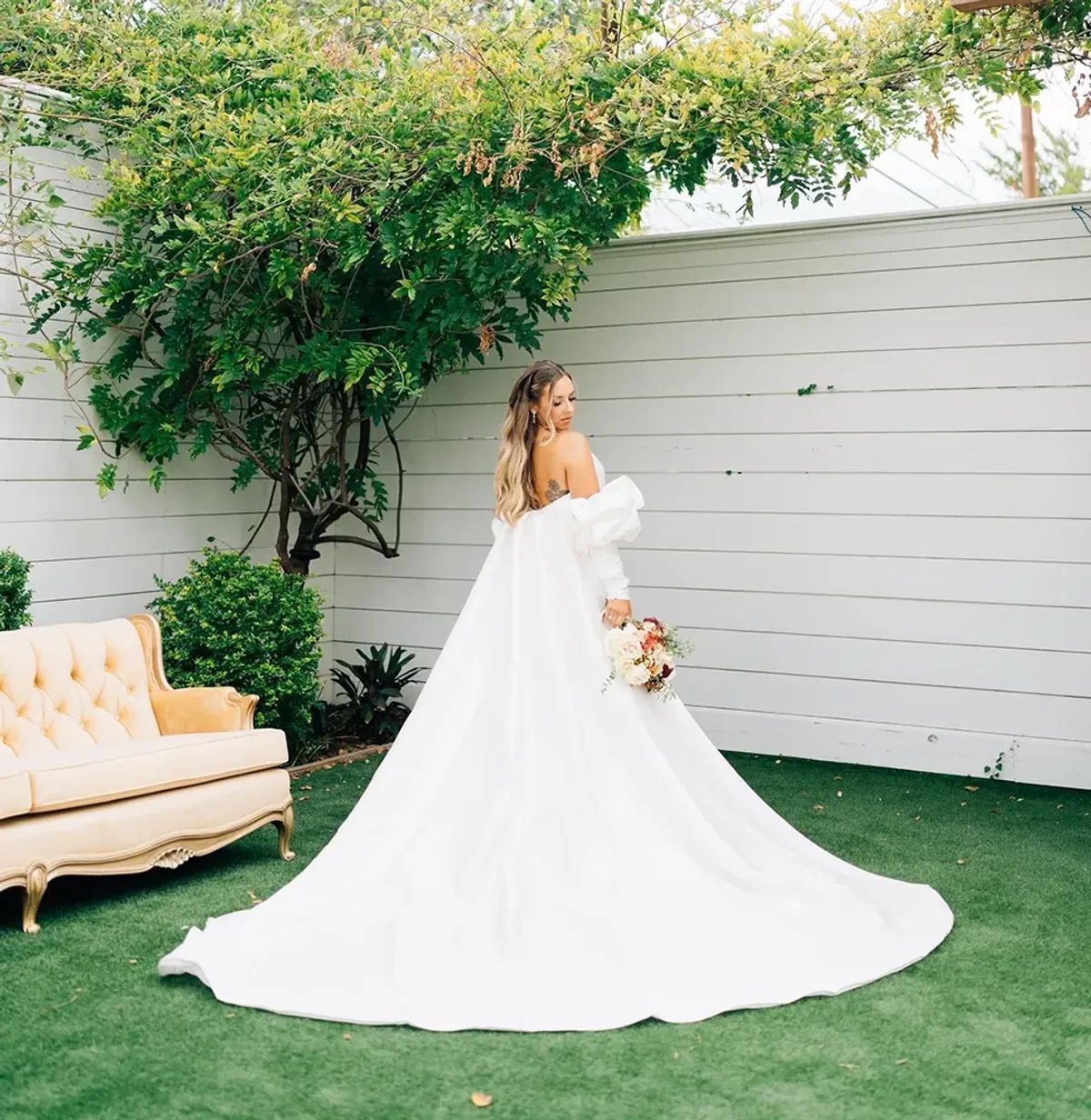 The bride is wearing a long white dress and holding a bouquet of flowers.