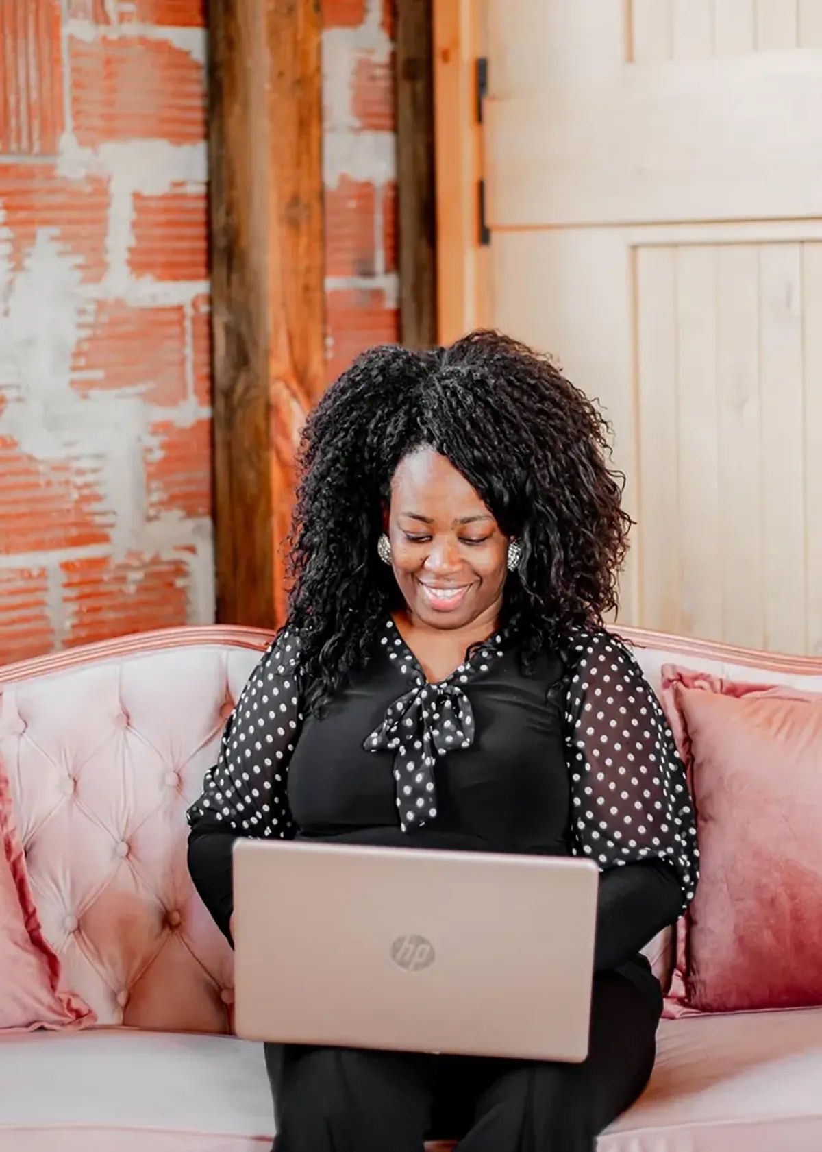 A woman is sitting on a couch using a laptop computer.