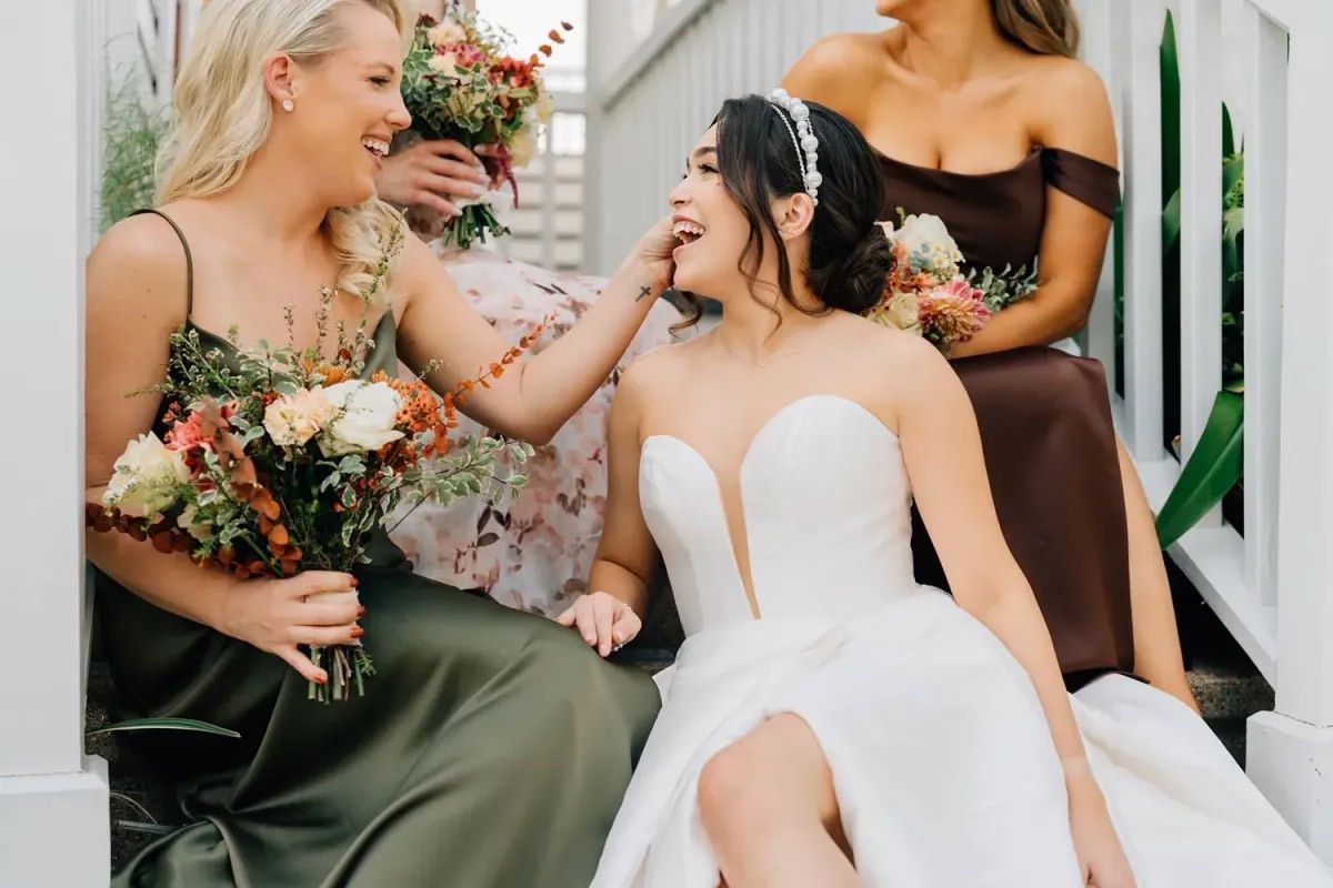 A bride and her bridesmaids are sitting on the steps of a building.