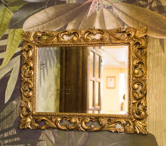 A mirror with a gold frame is hanging on a wall.