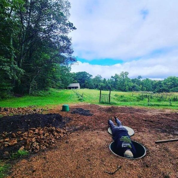 A man is laying on his back in a hole in the ground