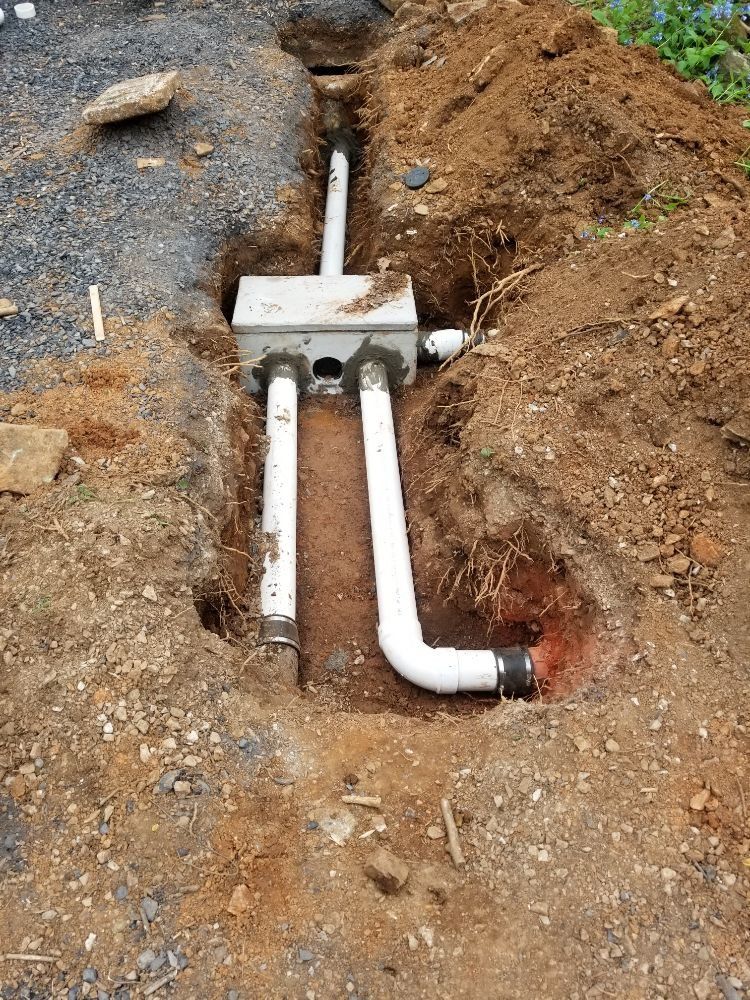 A drain pipe is being installed in a hole in the ground.