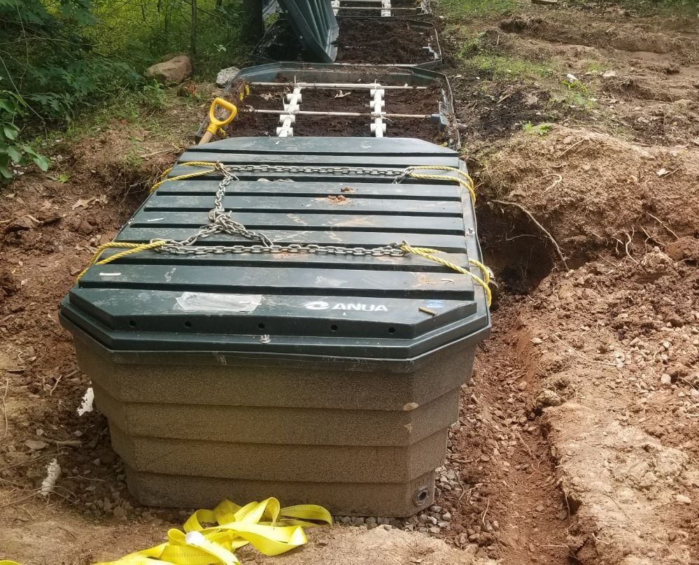 A large plastic container is sitting in the dirt next to a yellow strap.