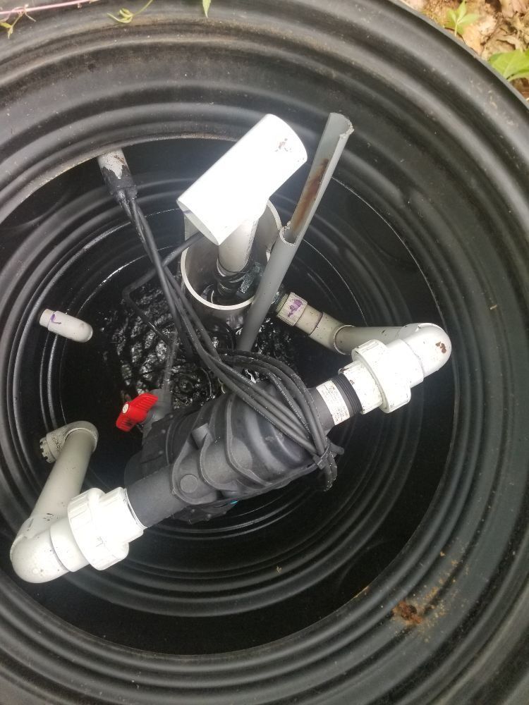 A close up of a drain with pipes and wires in it.