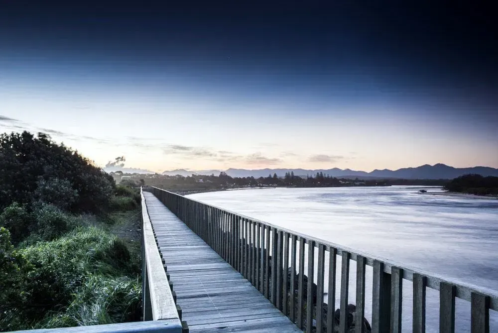 A Wooden Walkway Leading To A Body Of Water — D&C Projects in Coffs Harbour, NSW