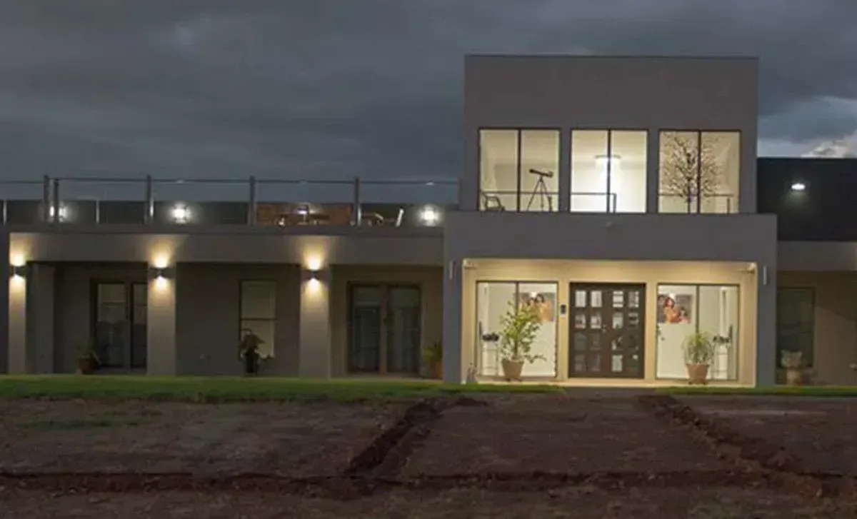 A Large House With A Lot Of Windows Is Lit Up At Night — D&C Projects in Charlestown, NSW