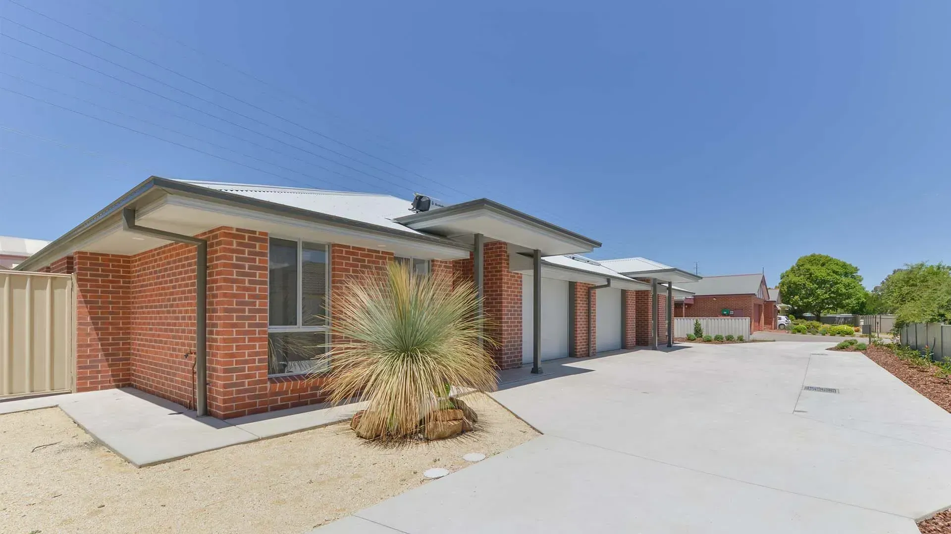 A Brick House With A Concrete Driveway And A Palm Tree In Front Of It — D&C Projects in Lake Macquarie, NSW