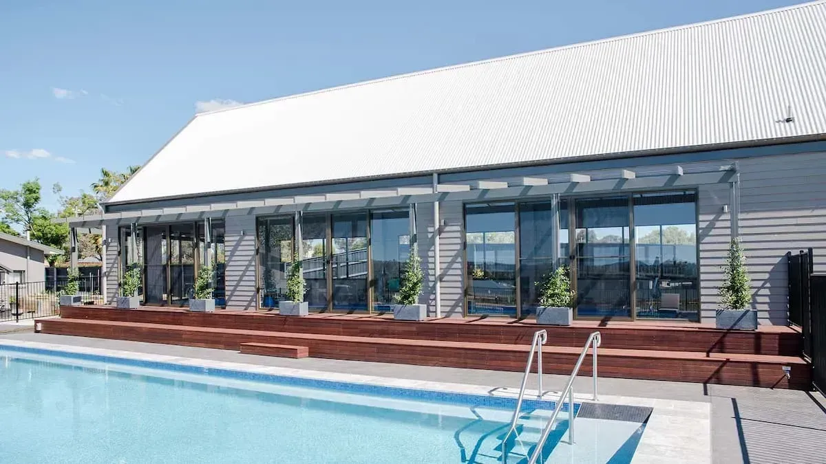 A Large House With A Swimming Pool In Front Of It — D&C Projects in Lake Macquarie, NSW