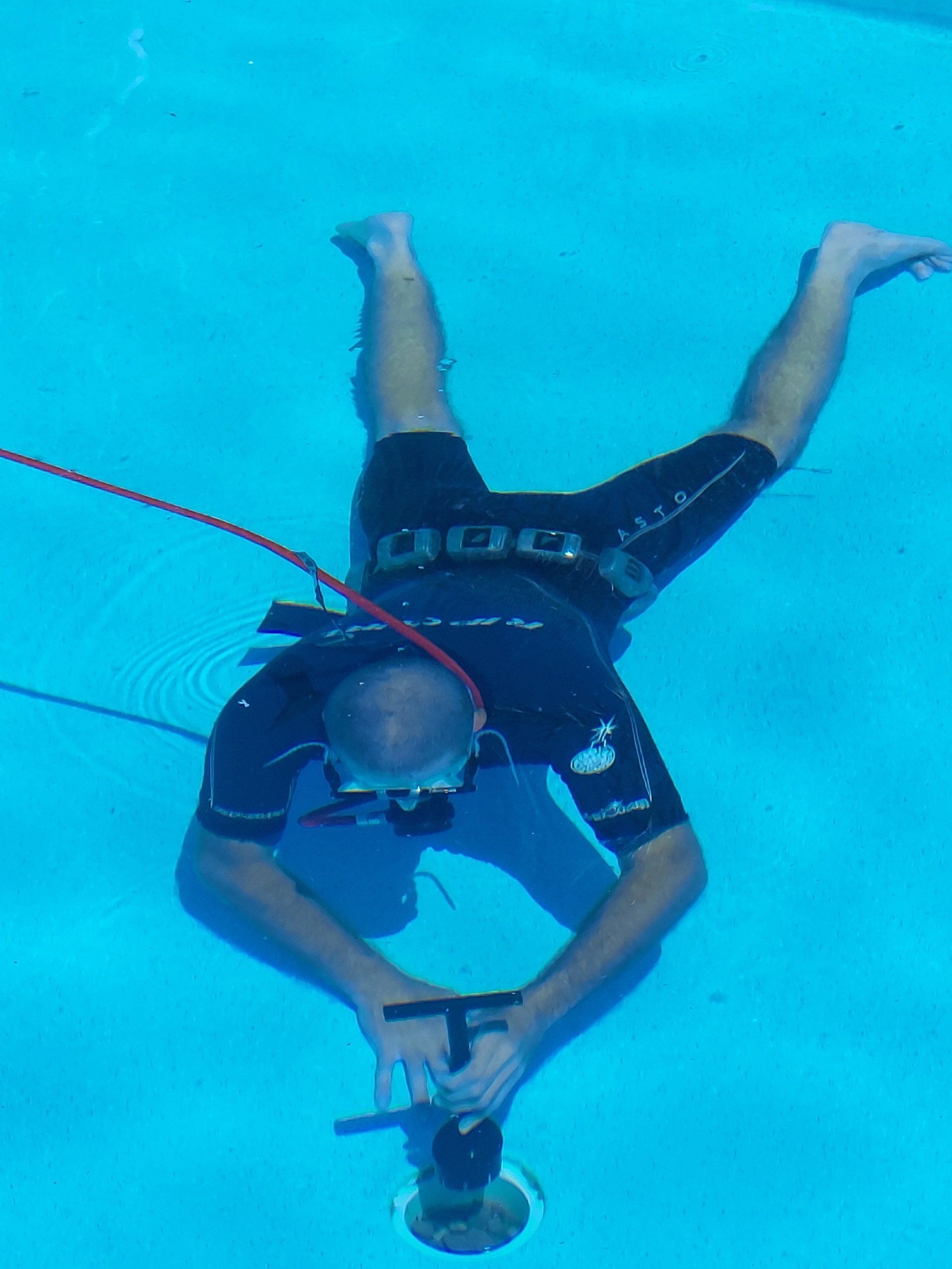 A man is doing a handstand in a swimming pool.